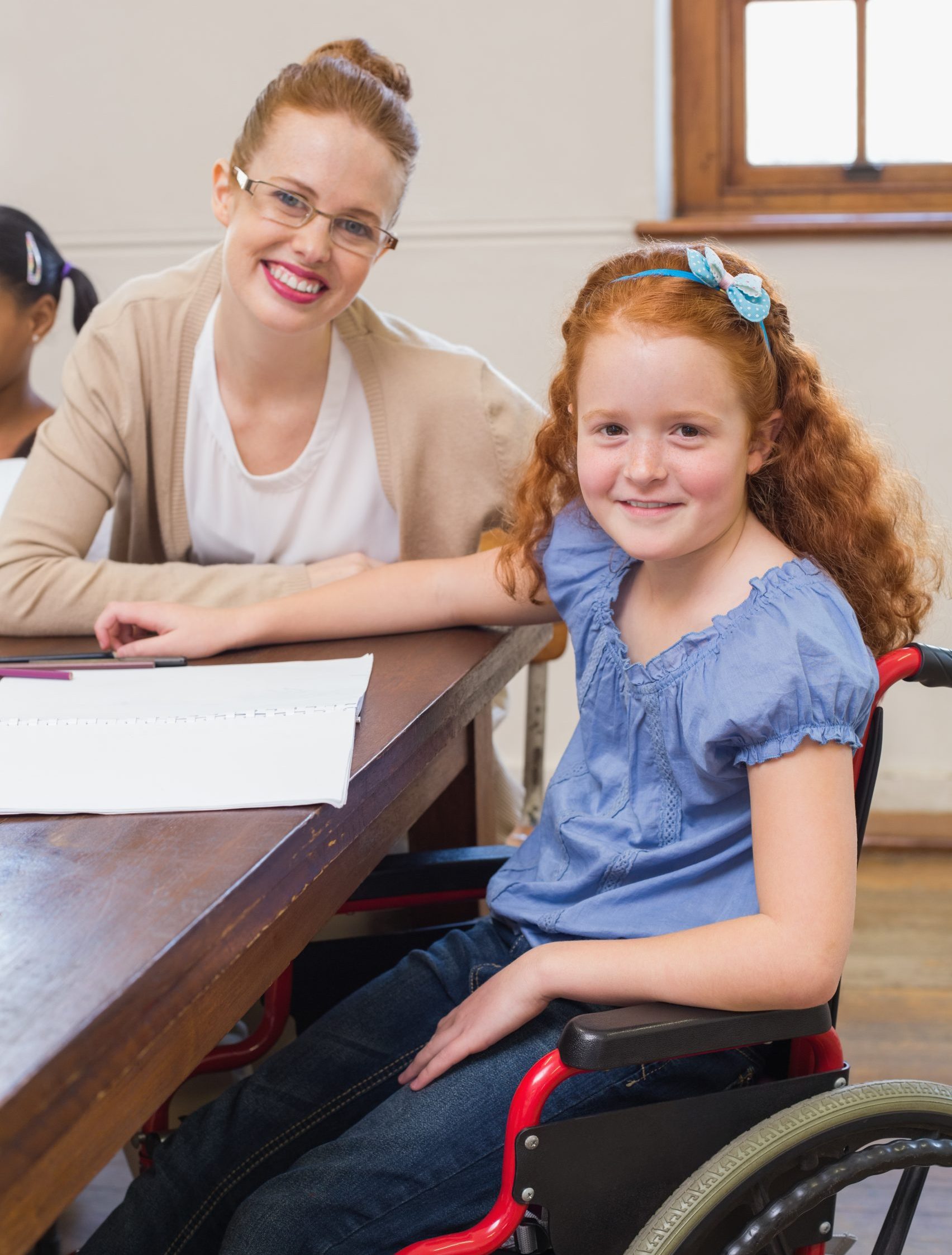 Pretty teacher helping pupil in classroom at the elementary school