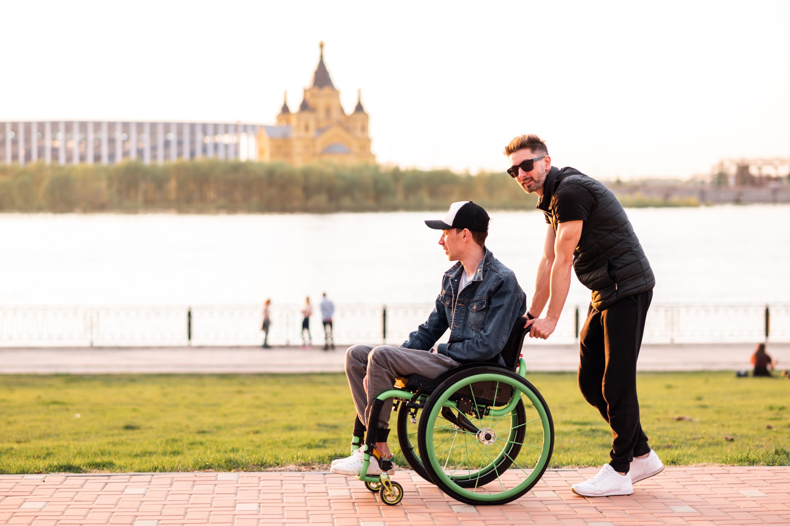 Help for people with physical disabilities. Man drive wheelchair and help his friend. Social services for population.