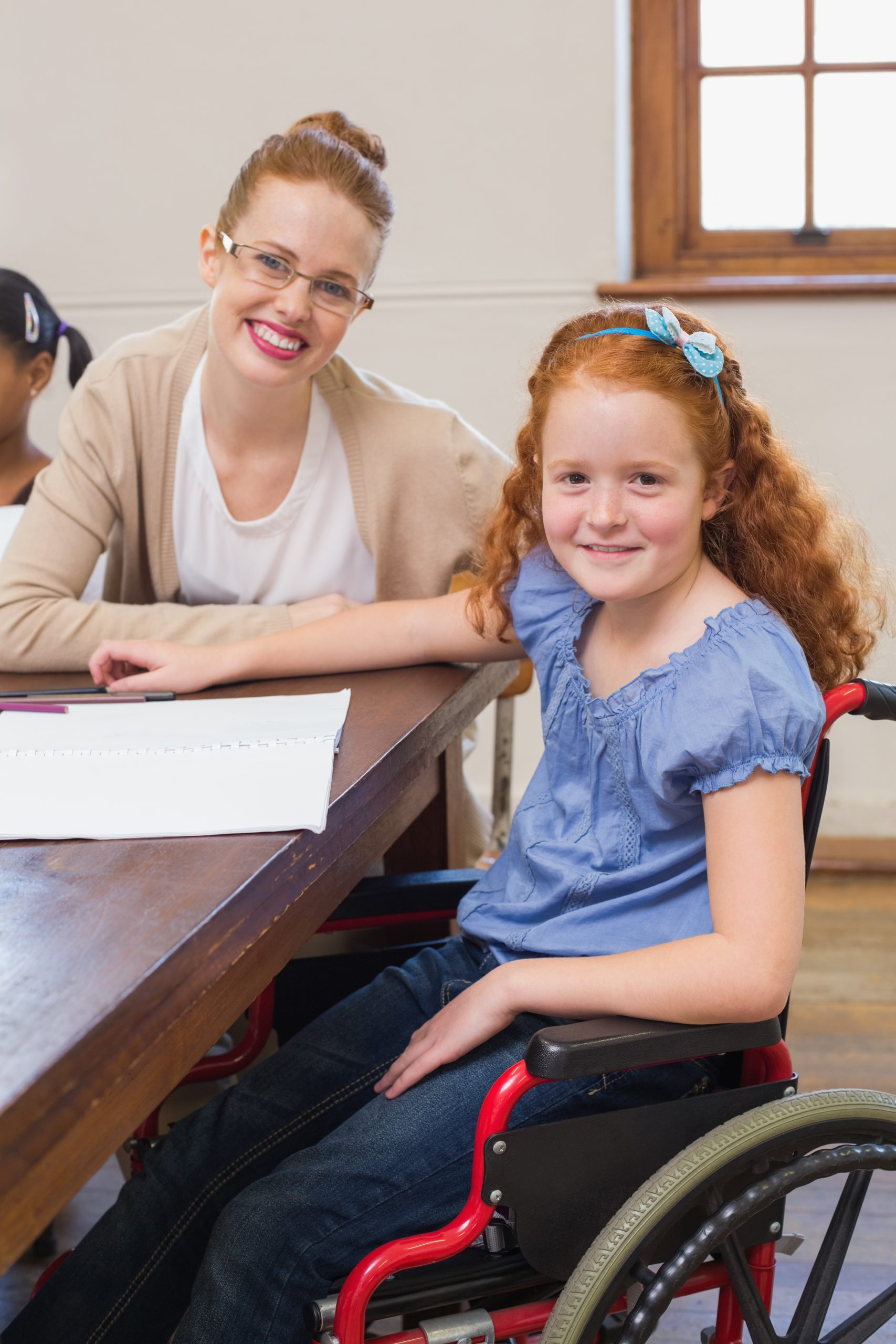 Pretty teacher helping pupil in classroom at the elementary school